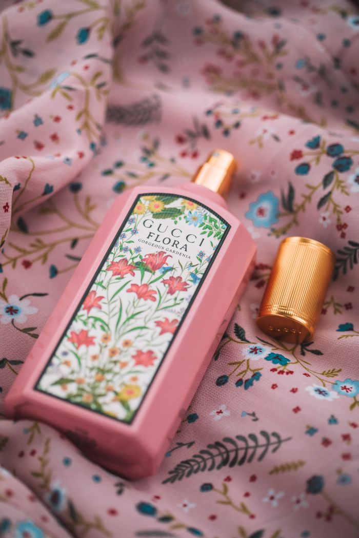 Close-up of a floral-themed perfume bottle on a decorative fabric, exuding elegance and fashion.